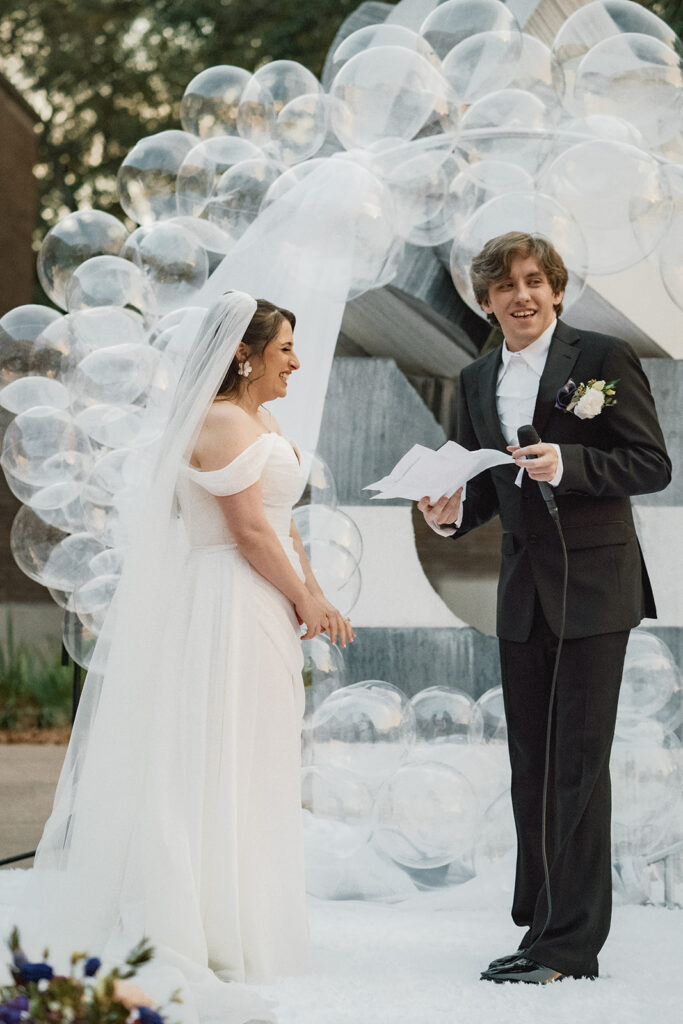 bride and groom laugh together reading vows at their ceremony