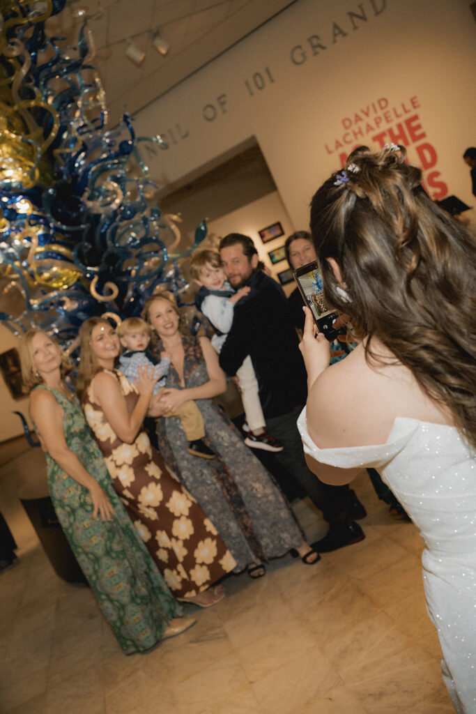 bride takes a photo of her friend's family during cocktail hour at the orlando museum of art