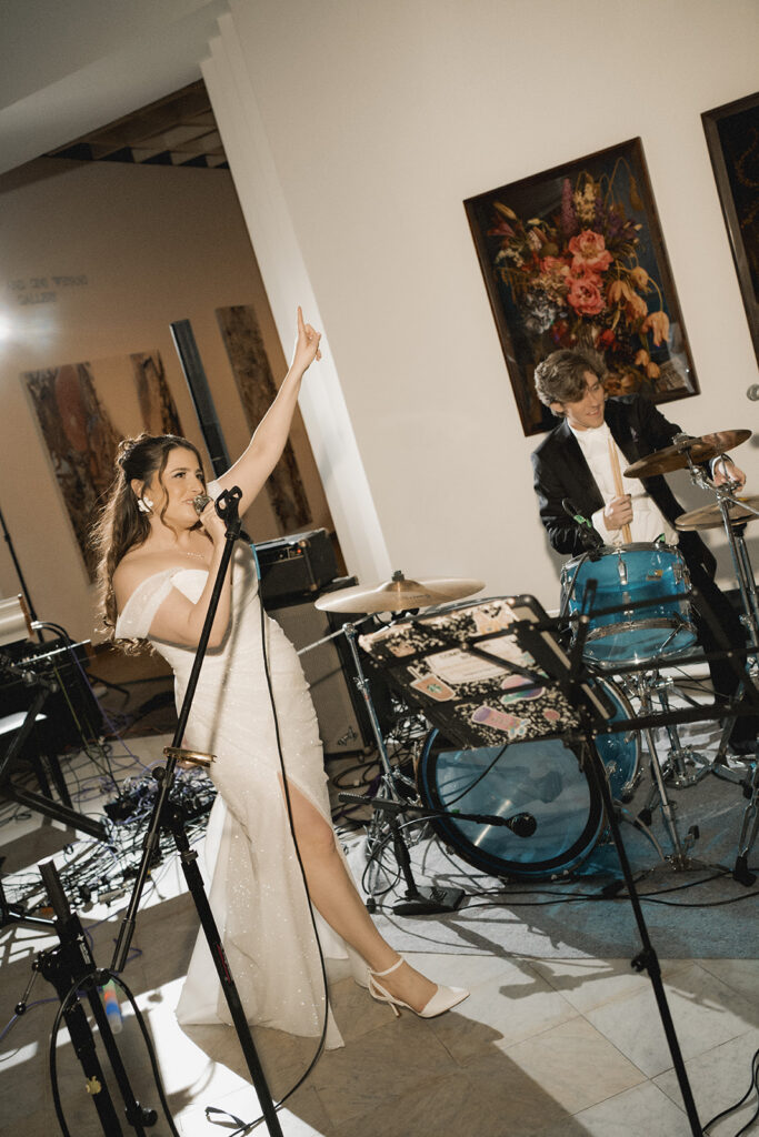 bride and groom play music together inside an art museum