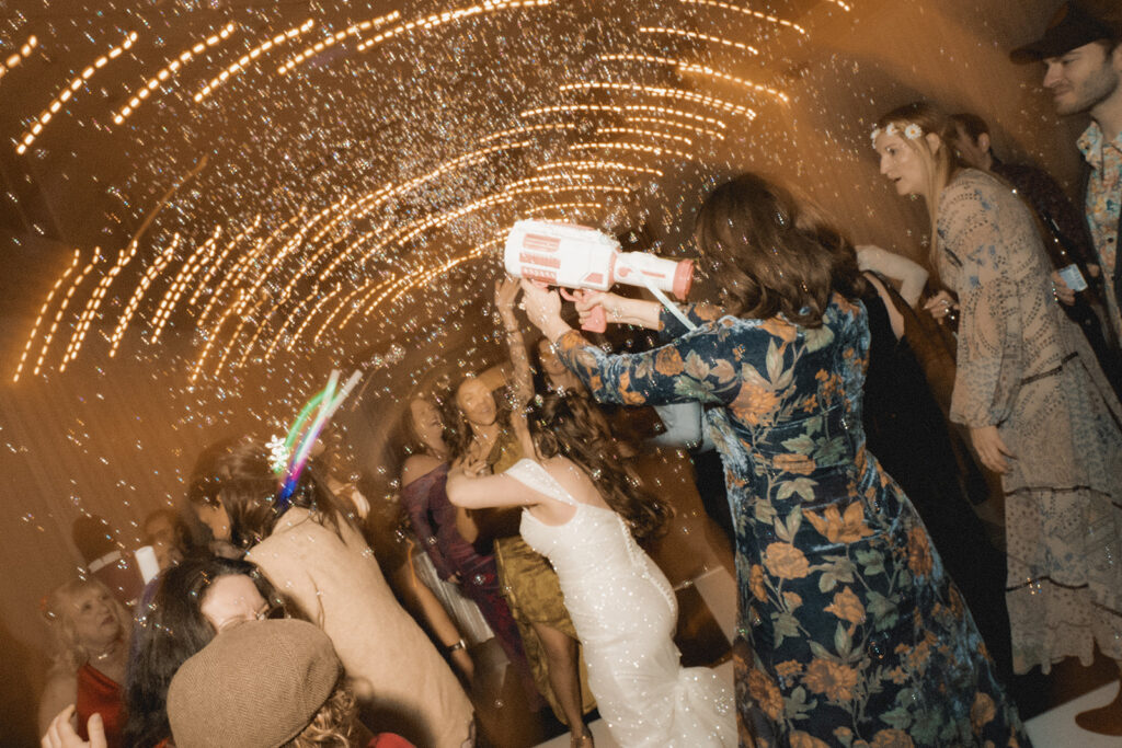 wedding guests have fun with a bubble gun during the party