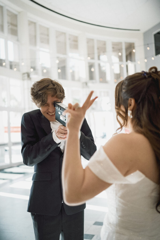 groom takes vintage video footage of his bride holding up a peace sign